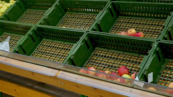 Mujer con un carrito de comestibles conduce más allá de estantes de frutas vacías — Vídeo de stock