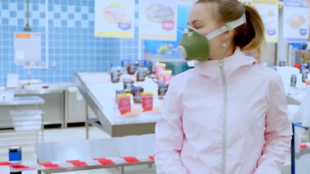 Una donna triste con una maschera medica si trova in un supermercato con un carrello della spesa. Dispositivi di protezione individuale contro il coronavirus. Una pandemia mondiale covid-19 . — Video Stock