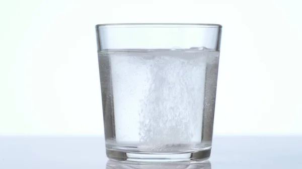 Tabletten fallen in Glas mit Wasser. Brausetablette Aspirin. Nahaufnahme auf weißem Hintergrund — Stockfoto