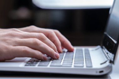 Dizüstü bilgisayarda çalışmak, klavyede yazmak, modern ofis işleri. Klavyede kadın eli izi var. Yakın plan..