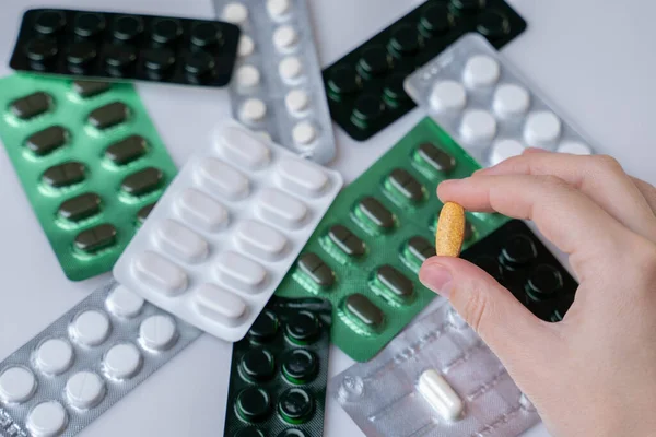 Mão segurando uma cápsula ou pílula isolada no fundo das embalagens de comprimidos — Fotografia de Stock