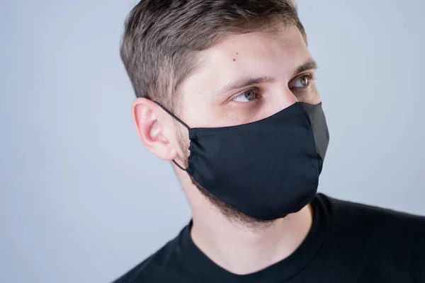 Um homem sobre um fundo cinzento com uma máscara preta — Fotografia de Stock