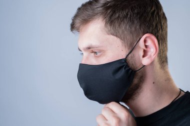 Siyah maskeli, gri arka planda bir adam