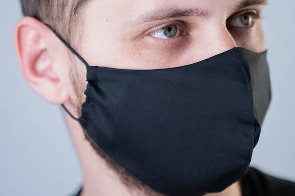 Young man wearing black face mask. Pandemic coronavirus covid-19 quarantine period concept.