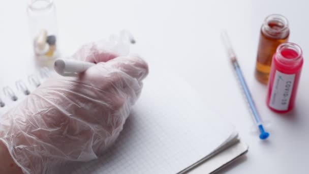 Un médecin en gants bleus écrit une ordonnance dans un carnet . — Video