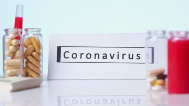 Arka planda CORONAVIRUS yazılı plaka haplar beyaz bir arkaplan. Roman Coronavirus COVID-19