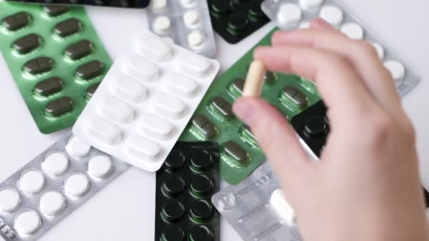 Hand met een capsule of pil geïsoleerd op de achtergrond van tabletverpakkingen — Stockvideo