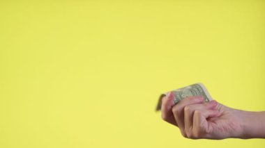 Eller 1 Amerikan dolarının düşüşünü yakalar ve sarı arka planda ağır çekimde düşer..