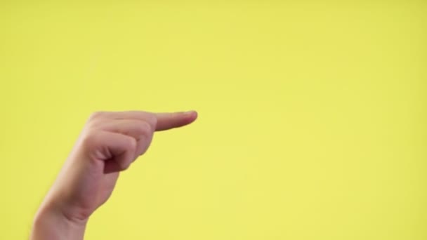 Nahaufnahme der abgeschnittenen Hand, die mit dem Finger auf den gelben Hintergrund zeigt — Stockvideo