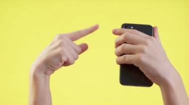 Adam cep telefonu kullanıyor, cep telefonu kullanıyor. Stüdyoda sarı arka planda parmak izlerini gösteriyor..