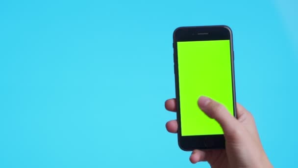 Femme main tenant un smartphone noir avec écran vert et toucher ou appuyer sur l'écran, Homme utilisant un téléphone mobile avec écran tactile chromatique sur fond bleu . — Video