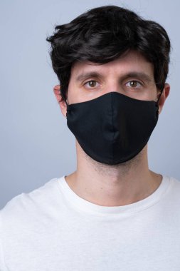 Siyah tıbbi maskeli bir adam, gri bir arka planda izole edilmiş.