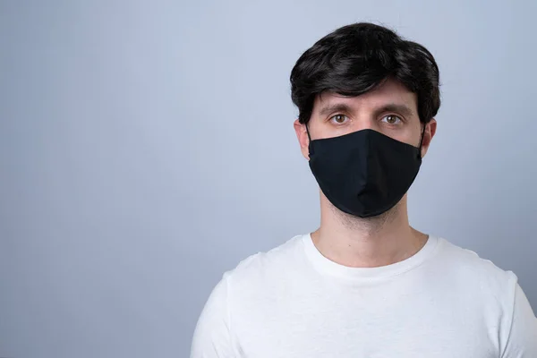 Homem em uma máscara médica preta, isolado em um fundo cinza — Fotografia de Stock