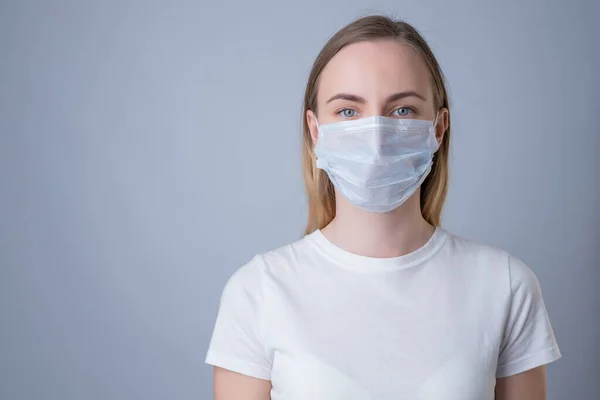 Mulher em uma máscara médica, isolada em um fundo cinza — Fotografia de Stock