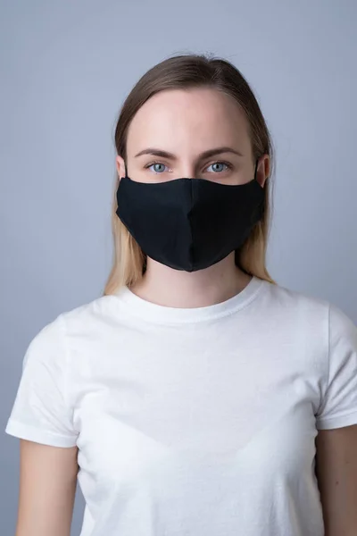 Mulher em uma máscara médica preta, isolada em um fundo cinza — Fotografia de Stock