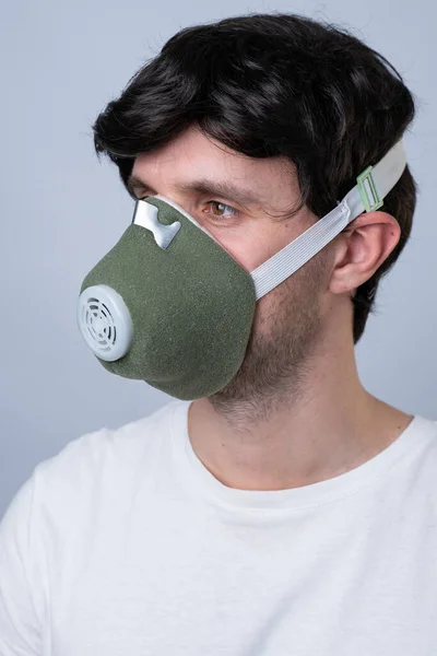 Homem em uma máscara respiratória, isolado em um fundo cinza — Fotografia de Stock