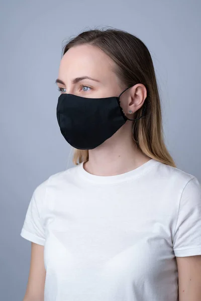 Жінка в чорній медичній масці, ізольована на сірому фоні — стокове фото