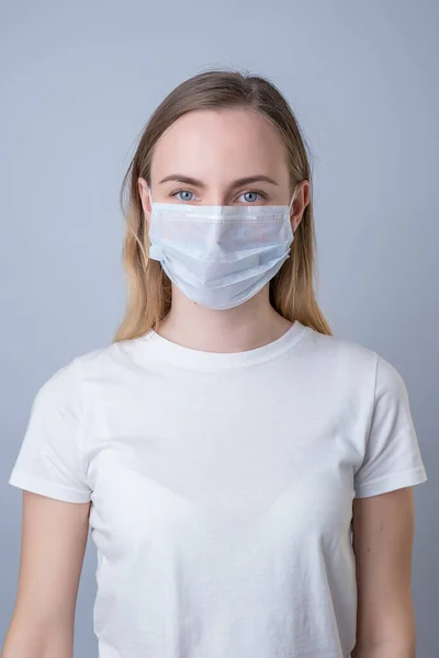 Mulher em uma máscara médica, isolada em um fundo cinza — Fotografia de Stock