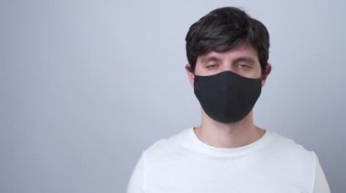 Siyah tıbbi maskeli bir adam, gri bir arka planda izole edilmiş.