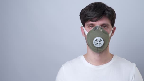 Homem em uma máscara respiratória, isolado em um fundo cinza — Vídeo de Stock