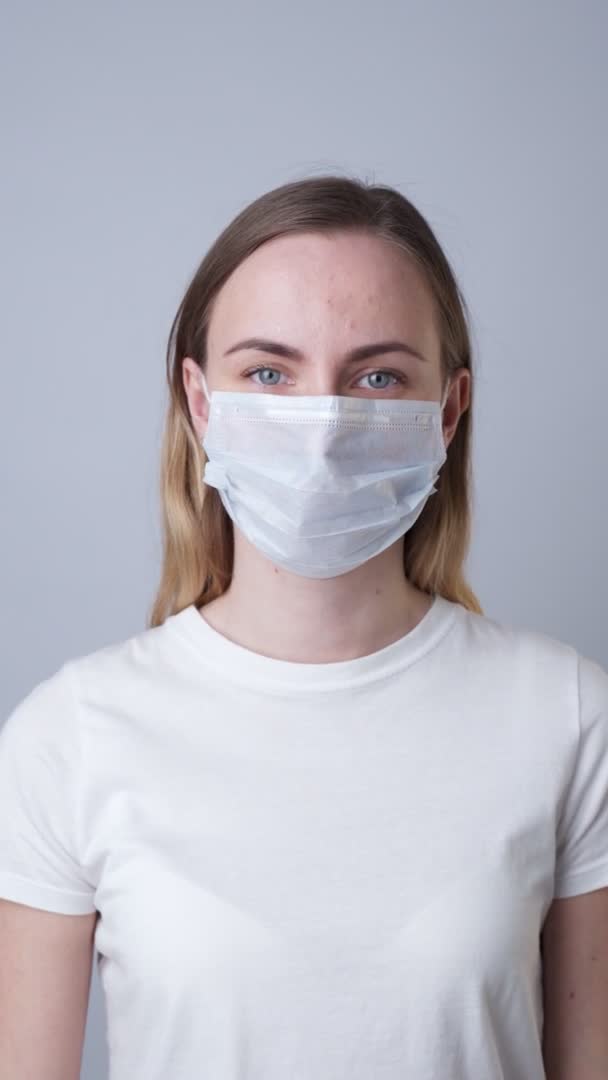 Vrouw met een medisch masker, geïsoleerd op een grijze achtergrond — Stockvideo