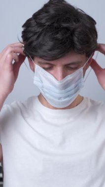 Dikey video. Adam yüzüne gri bir maske takıyor.
