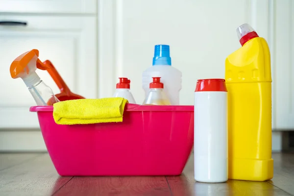 各种清洁剂和清洁剂的瓶子，地板上的粉红桶里的毛巾 — 图库照片