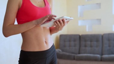 Evde tablet kullanan mutlu, genç bir spor kadını.