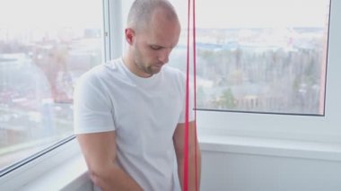 Genç bir atletik evde elastik bantlarla egzersiz yapıyor.