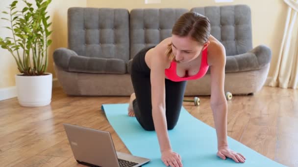 Retrato de la mujer en forma de entrenamiento en su sala de estar con ordenador portátil — Vídeos de Stock