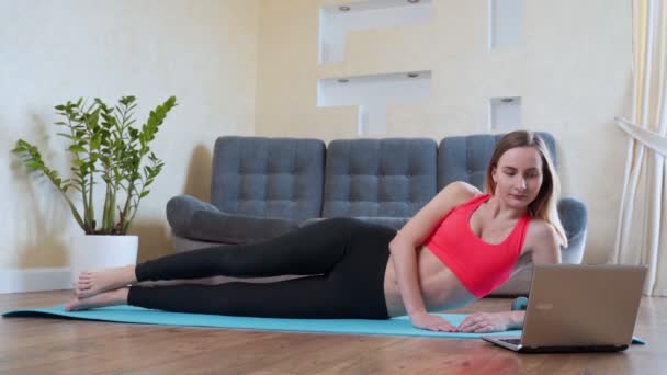 Retrato de la mujer en forma de entrenamiento en su sala de estar con ordenador portátil — Vídeo de stock