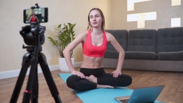 Sportowa blogerka w odzieży sportowej nagrywa wideo przed kamerą, gdy ćwiczy w domu w salonie. Koncepcja sportu i rekreacji. Zdrowy styl życia. — Wideo stockowe