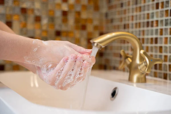 一名妇女在浴室洗手以防止Covid-19病毒感染。建议在大肠病毒大流行期间用肥皂和自来水冲洗. — 图库照片