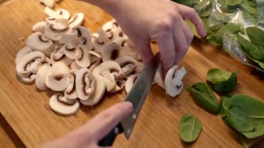 Masada mantar kesen kadın, yakın plan. Kesme tahtasında mantar kesen eller. Mutfakta mantar kesen genç bir kadın..