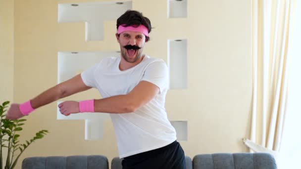 Funny estúpido hombre de fitness bailando disfrutando de la música y calentando en el entrenamiento en la sala de estar . — Vídeo de stock