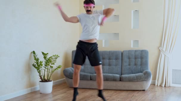 Komik görünüşlü fitness adamı dans ediyor müzikten hoşlanıyor ve oturma odasında egzersiz yapıyor.. — Stok video