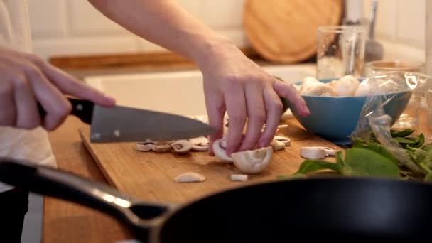 Woman cutting mushroom on table, close-up. Hands cutting mushrooms on a cutting board. Young woman cutting mushrooms in the kitchen. — Stock Video