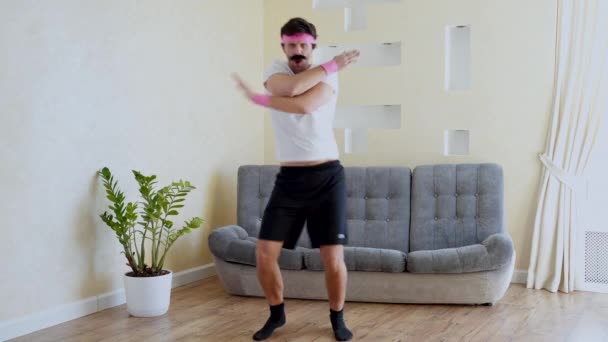 Funny estúpido hombre de fitness bailando disfrutando de la música y calentando en el entrenamiento en la sala de estar . — Vídeos de Stock