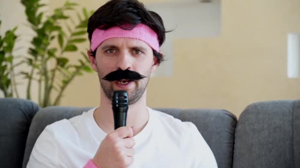 En lustig man med mustasch talar i en mikrofon. — Stockvideo