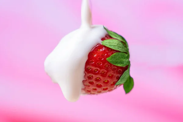 Cream being poured over a strawberry on a pink background — Stock Photo, Image