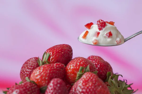 Yogur de fresa en una cuchara, sobre el fondo de fresas frescas — Foto de Stock