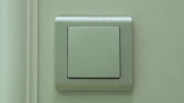 Свет выключен - женщина выключает кнопку на светло-серой стене, вид спереди — стоковое видео