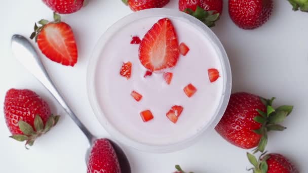 Bowl of delicious yogurt and strawberries rotates on the table. The view from the top — Stock Video