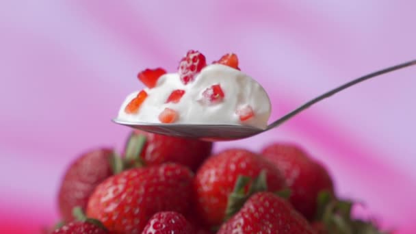 Yogur de fresa en una cuchara, sobre el fondo de fresas frescas — Vídeo de stock