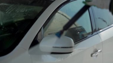 Bir adam oto yıkamada araba yıkıyor yüksek basınçlı araç yıkama makinesi suyla temizleniyor. Araba yıkama ekipmanı