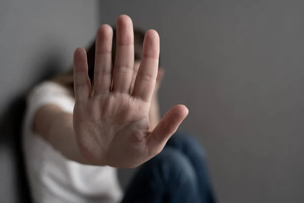 Konzept zur Beendigung geschlechtsspezifischer Gewalt. Frau, die auf dem Boden sitzt, hat den Arm ausgestreckt und die Handfläche geöffnet und macht die Stop-Geste. — Stockfoto