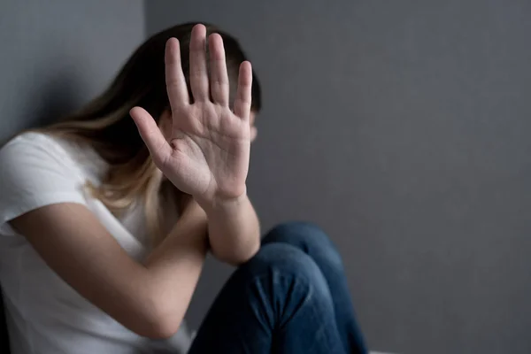 Concepto de parar la violencia de género. Mujer sentada en el suelo tiene el brazo extendido y la palma de su mano abierta haciendo el gesto de stop . —  Fotos de Stock
