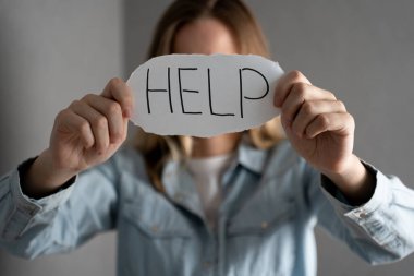 Kadın depresif bir ifade ve yardım mesajıyla bir makale gösteriyor. Kadınlara şiddet