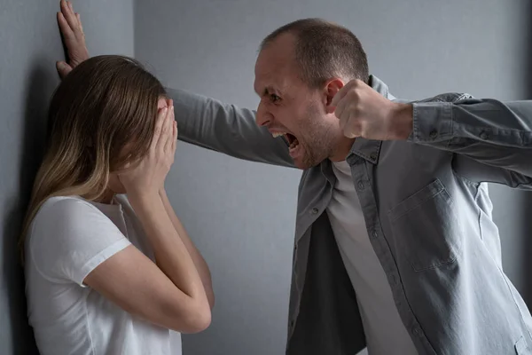 Marido enojado tratando de golpear a su esposa en el interior. Concepto de violencia doméstica — Foto de Stock