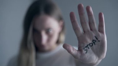 Yüzünde morluklar olan kadın dur işareti gösteriyor, avuç içi odaklı.